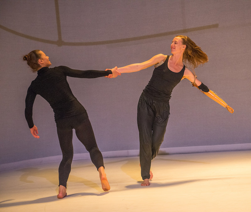 Two women clasp their right hands and spin in a circle